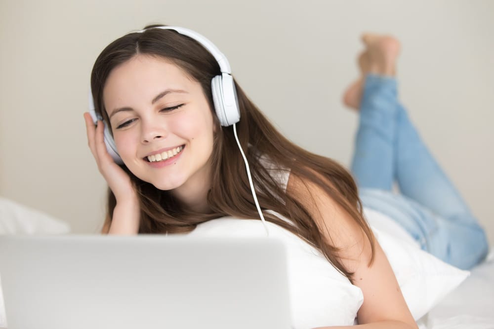Woman with headphones listening to music on laptop