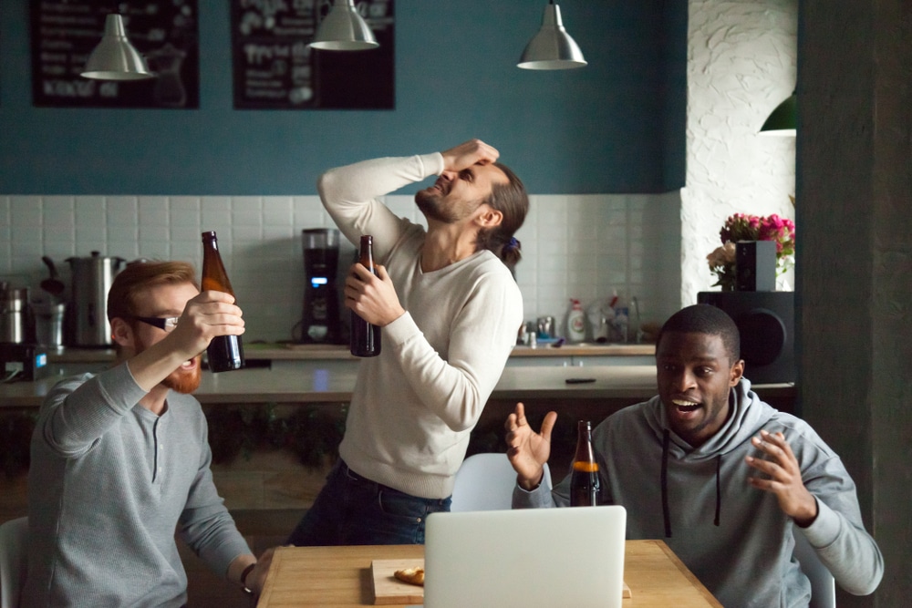 Group of men watching team lose on laptop