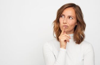 woman in white jumper thinking about investing in the ftse 100