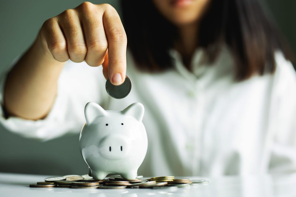 woman putting coin into pension pot piggy bank