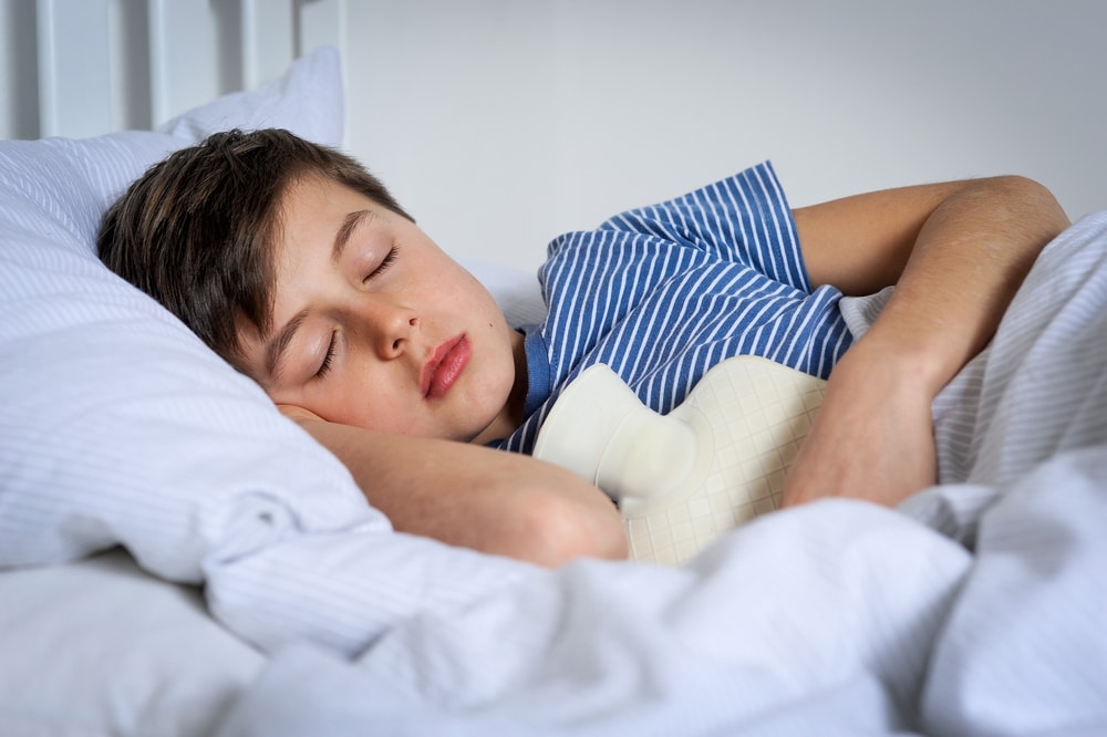 Young boy in bed asleep with hot water bottle